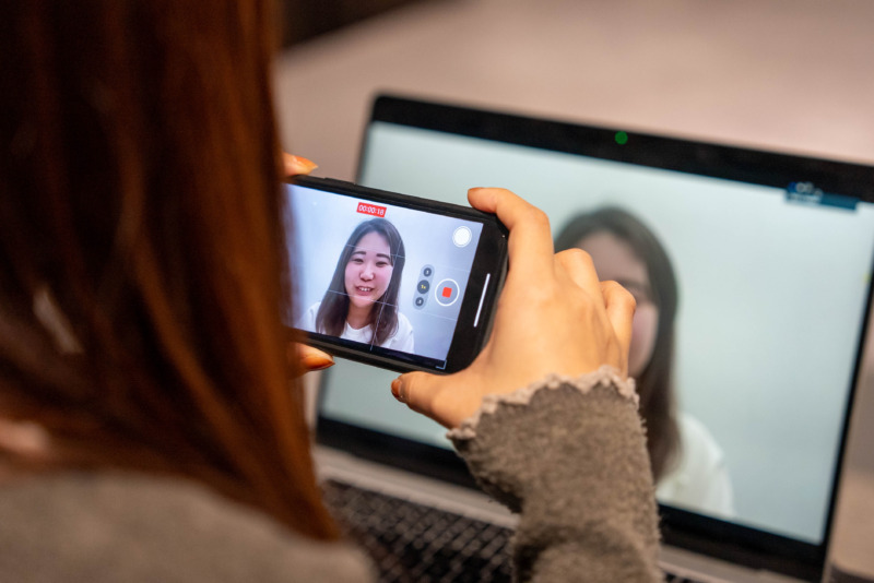 受講者がパソコン越しに話す姿をスマートフォンで撮影するようす