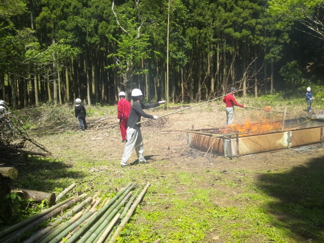 鹿野山自然学校が提供する自然体験で、森の中で切った竹を燃やしている人々