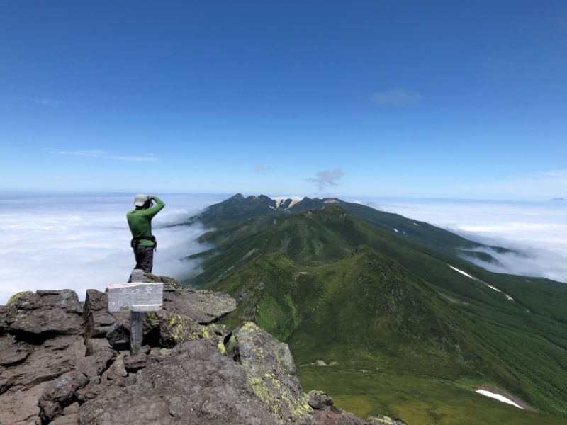 北海道知床アルパ株式会社で登頂後に景色を撮影する男性